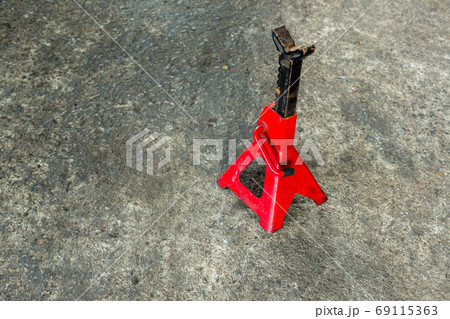 Red axle stand on floor. Red high lift jack stand on the floor. 69115363
