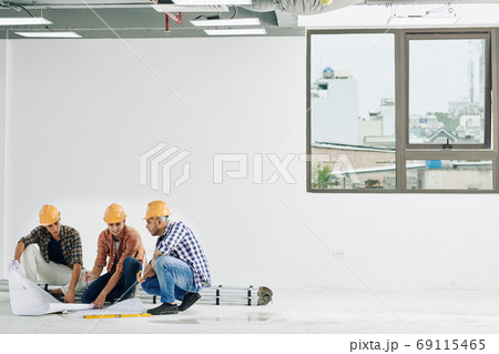 Construction workers checking blueprints 69115465
