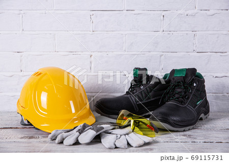 A helmet and safety shoes are essential personal accessories for every employee in the profession of a builder. A helmet and safety shoes are essential personal accessories for every employee in the profession of a builder. 69115731