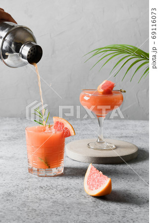 Pouring grapefruit cocktail in glass. Vertical format. 69116073