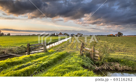 Cloudscape over gate in lowland meadow Cloudscape over gate in lowland meadow 69116262