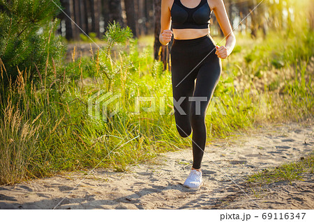Legs of running girl sportswoman on road in forest 69116347