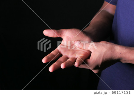 man with hand pain isolated in black. man with hand pain isolated in black. 69117151