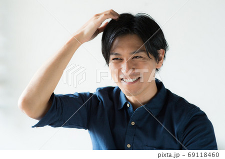 頭をかく若い男性 69118460