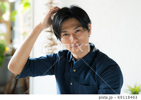 頭をかく若い男性の写真素材