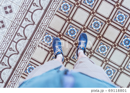 Old tiles of historical building of Saigon Central Post Office (Ho Chi Minh City, Vietnam) constructed between 1886-1891. Beautiful detail of the interior, a selfie of blue sneakers on tiled floor. Old tiles of historical building of Saigon Central Post Office (Ho Chi Minh City, Vietnam) constructed between 1886-1891. Beautiful detail of the interior, a selfie of blue sneakers on tiled floor. 69118801