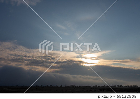 Sunset and looming fog. Trees and bushes in the distance. 69122908