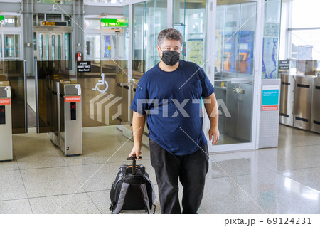 Man traveler with suitcase on wheels wears Man traveler with suitcase on wheels wears 69124231