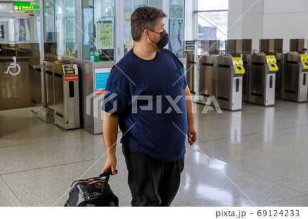 Man in protective medical masks with a suitcase 69124233