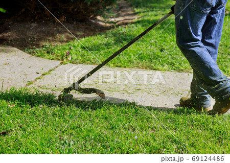 The gardener man mows the grass with a hand lawn 69124486