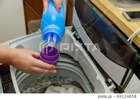 Woman hand pours liquid powder into the drum of Woman hand pours liquid powder into the drum of 69124658