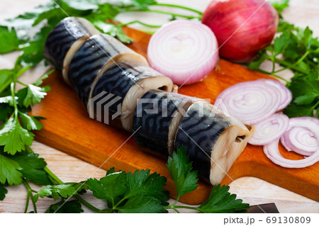 Lightly salted mackerel cut into pieces with parsley and onion on table 69130809