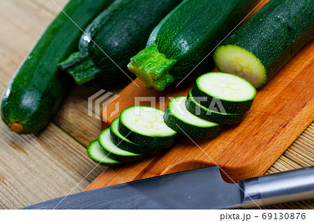 Whole and sliced fresh zucchini on wooden table Whole and sliced fresh zucchini on wooden table 69130876