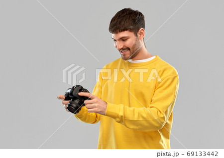 smiling young man with digital camera smiling young man with digital camera 69133442