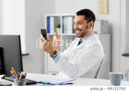 doctor with smartphone having video call at clinic 69133783
