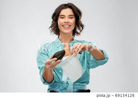 happy woman putting avocado into reusable bag 69134126