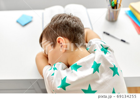 close up of tired boy sleeping on table at home close up of tired boy sleeping on table at home 69134255