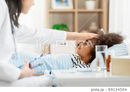 doctor with clipboard and sick girl in bed at home doctor with clipboard and sick girl in bed at home 69134504