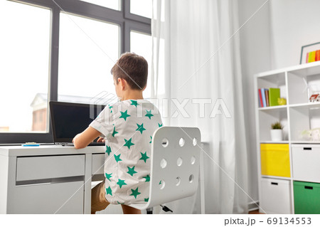 student boy typing on laptop computer at home 69134553