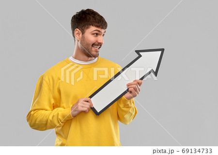 smiling man holding big arrow pointing to right smiling man holding big arrow pointing to right 69134733