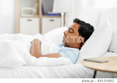 indian man sleeping in bed at home 69134902