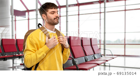 sad unhappy young man with backpack over airport 69135014