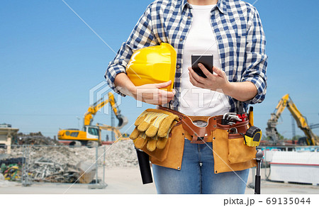 woman or builder with phone and working tools 69135044