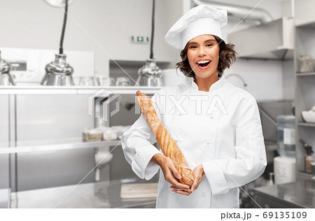 happy female chef with french bread or baguette 69135109