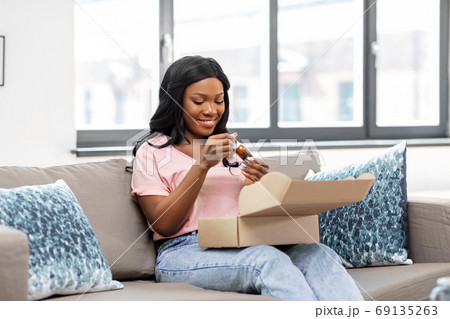 african american woman opening parcel box at home 69135263