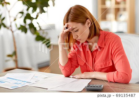 woman with calculator and papers working at home 69135487