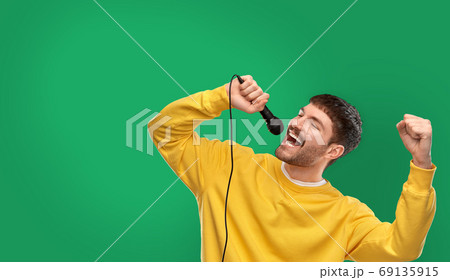 man in yellow sweatshirt with microphone singing 69135915