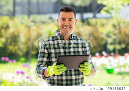 happy man with tablet pc at summer garden happy man with tablet pc at summer garden 69136035