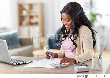 woman with calculator and papers working at home woman with calculator and papers working at home 69136217