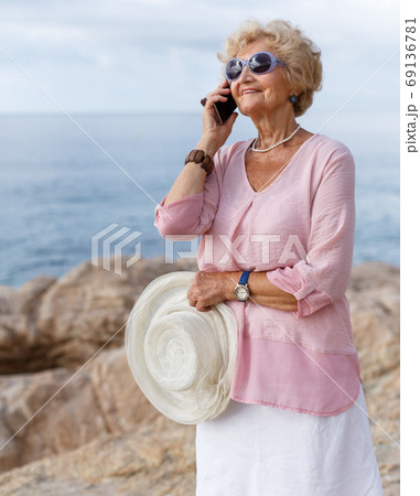 Aged woman talking on phone outdoors Aged woman talking on phone outdoors 69136781