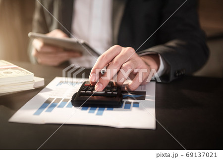 Businesswoman working with tablet and using a calculator to calculate the numbers of static in office. Finance accounting concept. Businesswoman working with tablet and using a calculator to calculate the numbers of static in office. Finance accounting concept. 69137021