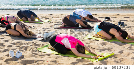 People practicing yoga on beach People practicing yoga on beach 69137235