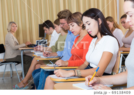 Side view of student group with female teacher on lecture 69138409