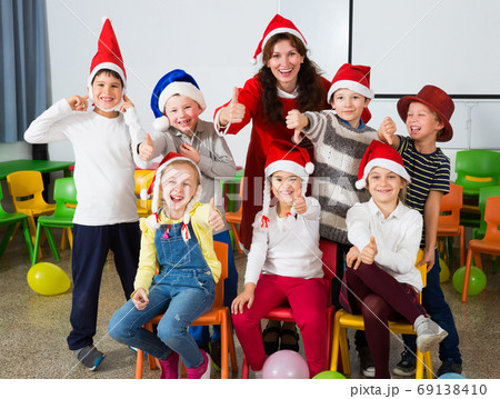 Pupils with teacher in Santa hats giving thumbs up 69138410