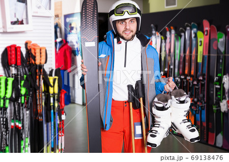 Smiling man posing in skiing gear in sport equipment shop Smiling man posing in skiing gear in sport equipment shop 69138476