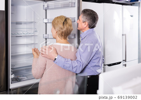 Mature couple chooses refrigerator in store 69139002