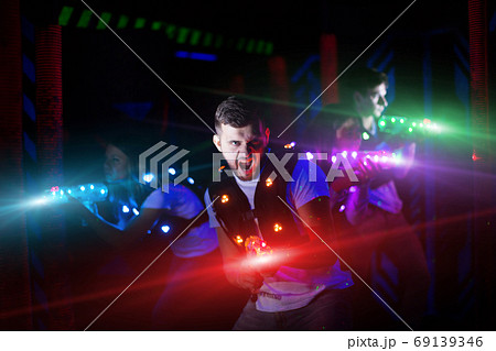 Guy in colored beams during laser tag game Guy in colored beams during laser tag game 69139346