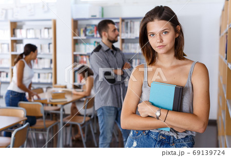Young woman with book in library Young woman with book in library 69139724