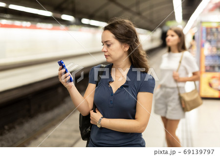 Woman with phone waiting at underground station Woman with phone waiting at underground station 69139797