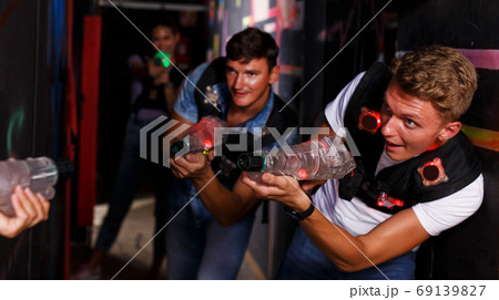 friends standing with laser guns during laser tag game friends standing with laser guns during laser tag game 69139827