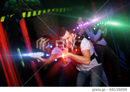 Excited guy laser tag player in bright beams 69139899