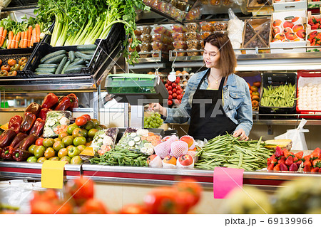 Adult woman seller weighing fruit and vegetables Adult woman seller weighing fruit and vegetables 69139966