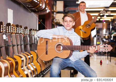 Boy and father choosing acoustic guitar 69140664