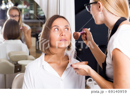 female makeup artist applying cosmetics for woman 69140959