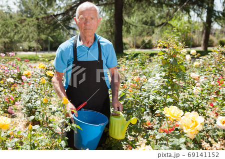 Man with bucket at flower bed Man with bucket at flower bed 69141152