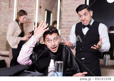 Unpleasantly surprised man and hairdresser regretting in salon Unpleasantly surprised man and hairdresser regretting in salon 69141348